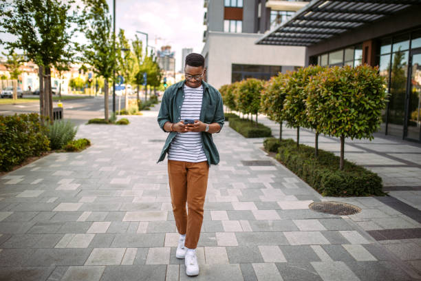 istock Young man walking down the street, using mobile phone 1327703314