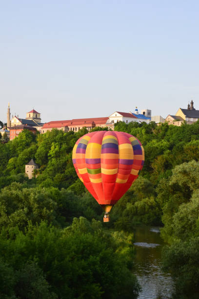 istock A large multi-colored balloon flies very low over the river and between dense trees. In the background, the buildings of the ancient city 1327703475