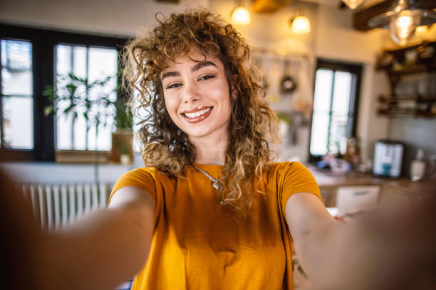 Selfie from the kitchen Beautiful young woman, a social media influencer recording a video tutorial of preparing food for her youtube food channel and taking selfies with her camera. women taking selfies photos stock pictures, royalty-free photos & images