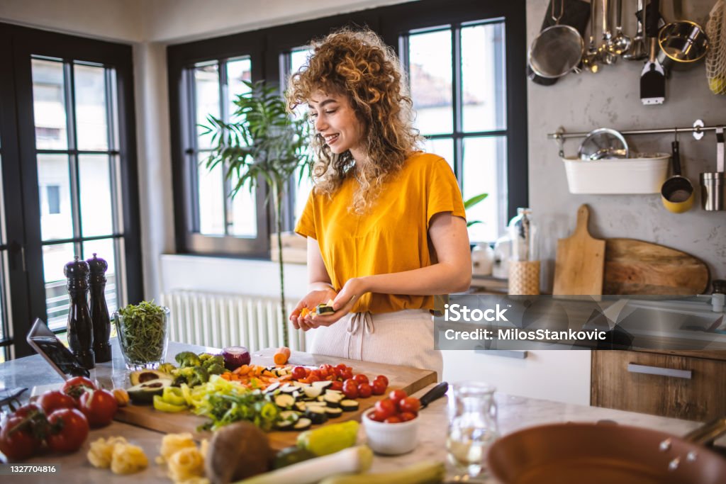 Young women making healthy meal in the kitchen Photo of young women making healthy meal in the kitchen and reading recipe from the digital tablet. 20-29 Years Stock Photo