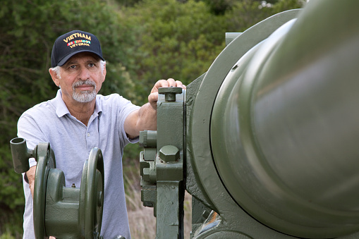 Vietnam Veteran with veteran cap at outdoor World War Two museum.
