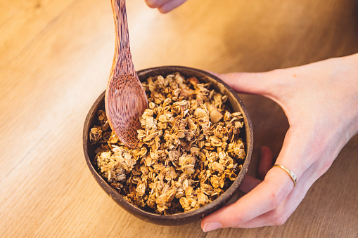 Close up woman hands holding a bowl of homemade granola.