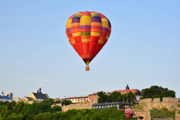 istock A large multicolored hot air balloon flies low over ancient buildings and a tree-lined valley. Photographed at close range 1327714645
