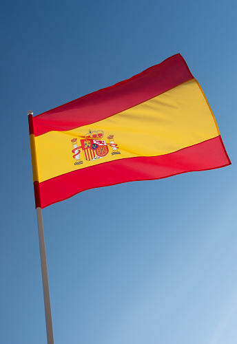 Flag of Spain on blue sky background.
