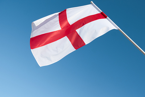 Flag of England on blue sky background.