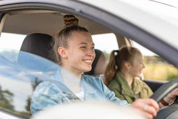 orgogliosa giovane donna alla guida di amici nella sua prima auto - car insurance women driving foto e immagini stock