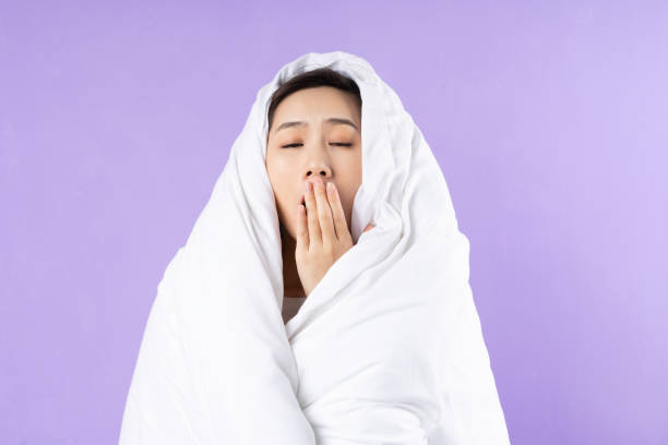 Asian woman curled up in blanket on purple background Asian woman curled up in blanket on purple background hot filipina women stock pictures, royalty-free photos & images