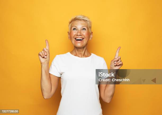 Senior Woman With Short Hair Pointing With Fingers And Raised Arms Stock Photo - Download Image Now