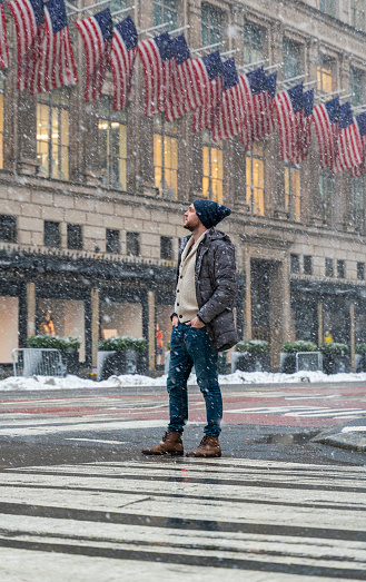 A man crossing the street in a big city under a snowfall during the winter storm.