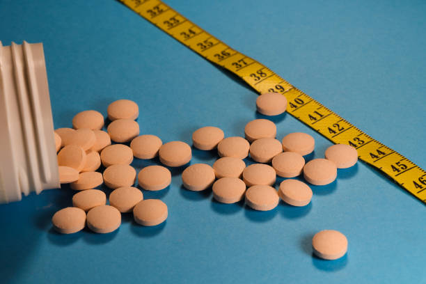 istock Spilled Pill Container With Measuring Tape On Blue 1327735638