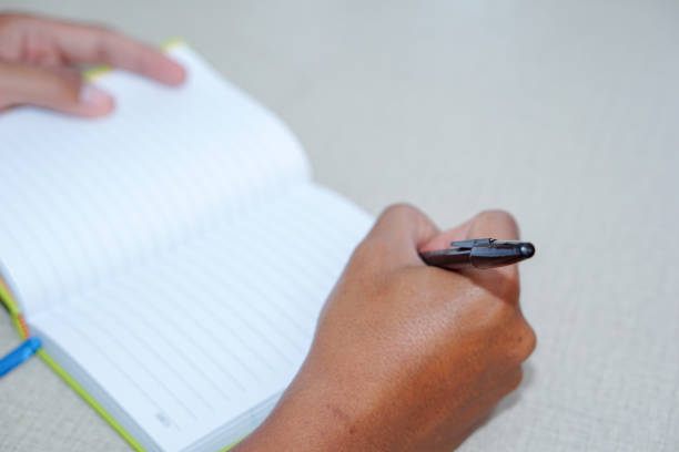 istock hand man writing in a blank striped notebook on a work desk 1327739709