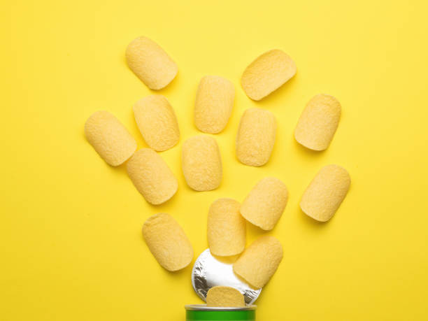 istock Potato chips fall out of the jar on a yellow background. Flat lay. 1327740618