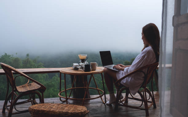 istock A woman using and working on laptop computer while sitting on balcony with a beautiful nature view on foggy day 1327744845