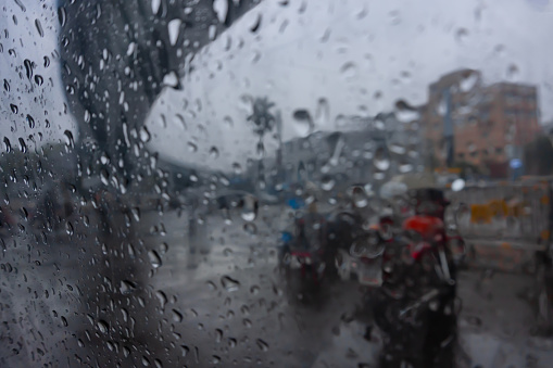 Image shot through raindrops falling on wet glass, abstract blurs of traffic - monsoon stock image of Kolkata (formerly Calcutta) city ,