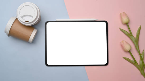 istock Top view digital tablet, coffee cup and pink tulips on blue and pink background. 1327747535