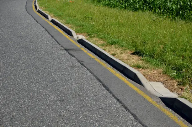 Photo of installation of concrete curbs with gaps that let water into the park into the ditch, where it seeps into the grass and does not drain into the sewer, kerbside