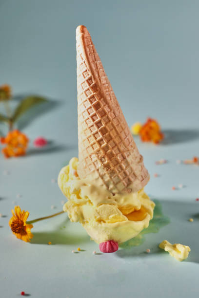 istock Mango ice cream with waffle cone on blue background with yellow flowers 1327753026