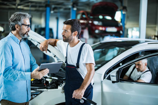 istock Manager and auto mechanic talking while working on digital tablet in a repair shop. 1327756016