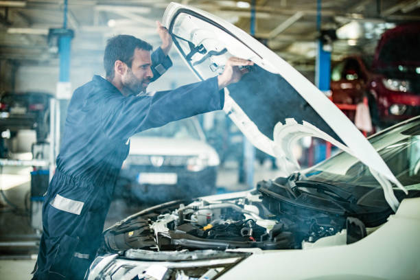 istock Auto mechanic examining overheated car in a workshop. 1327756061