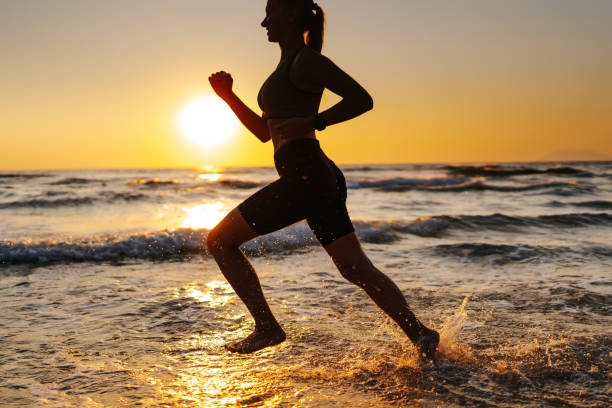 istock Young woman running on the beach at sunset 1327757505