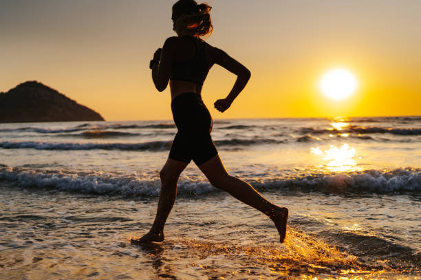 istock Young woman running on the beach at sunset 1327757567