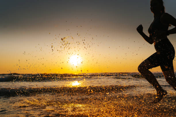 istock Young woman running on the beach at sunset 1327757594