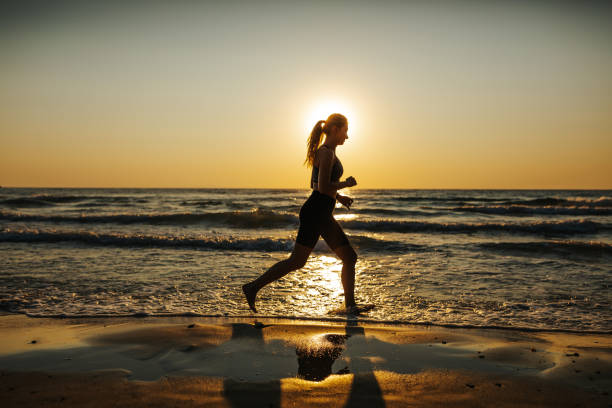 istock Young woman running on the beach at sunset 1327757626