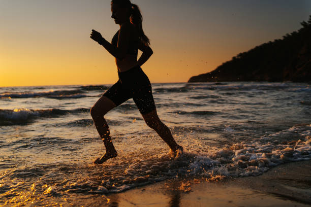 istock Young woman running on the beach at sunset 1327757633
