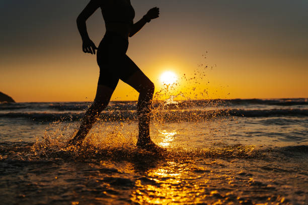 istock Young woman running on the beach at sunset 1327757666