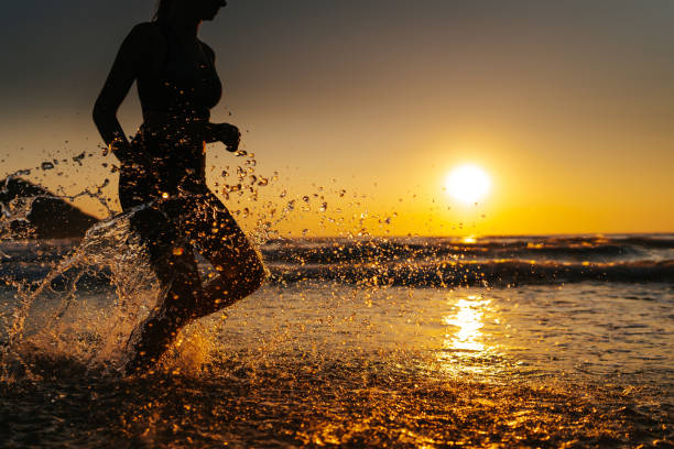 istock Young woman running on the beach at sunset 1327757717