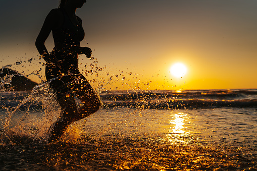 Young woman running on the beach at sunset