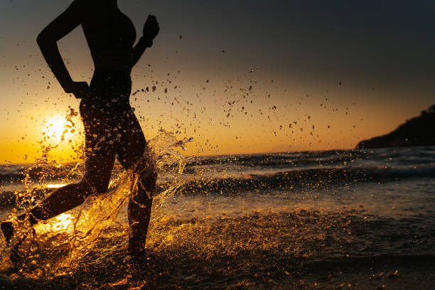 istock Young woman running on the beach at sunset 1327757818