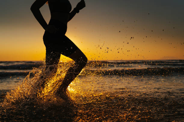 istock Young woman running on the beach at sunset 1327757833