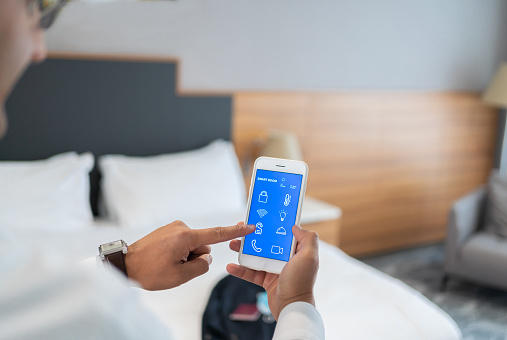 Businessman Using Smart Room Application On Smartphone screen İn Hotel Room