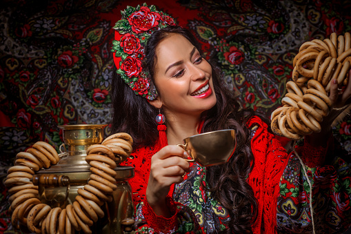 Female Russian beauty queen in a traditional dress with a samovar and pretzels