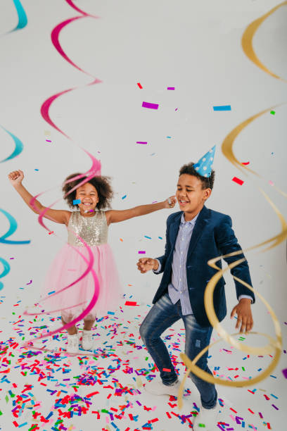 istock Happy girl and boy in party hat dancing on white background 1327763542
