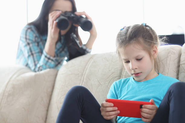 Mom controls her daughter with phone through binoculars Mom controls her daughter with phone through binoculars. Best parental controls and smartphone apps concept spy games stock pictures, royalty-free photos & images