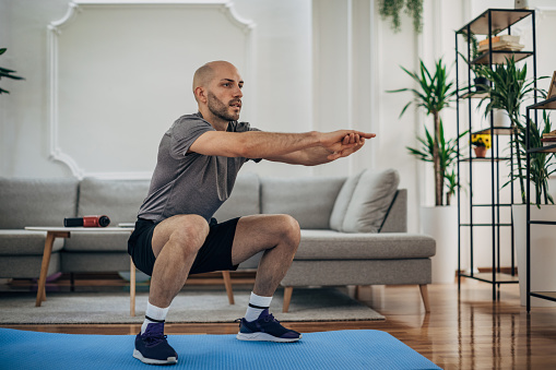 One man, male exercising in living room on the floor alone at home.