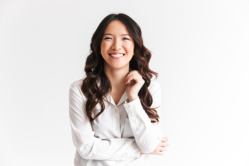 Retrato de una hermosa mujer asiática con el pelo largo y oscuro riéndose de la cámara con una hermosa sonrisa, aislada sobre fondo blanco en el estudio photo