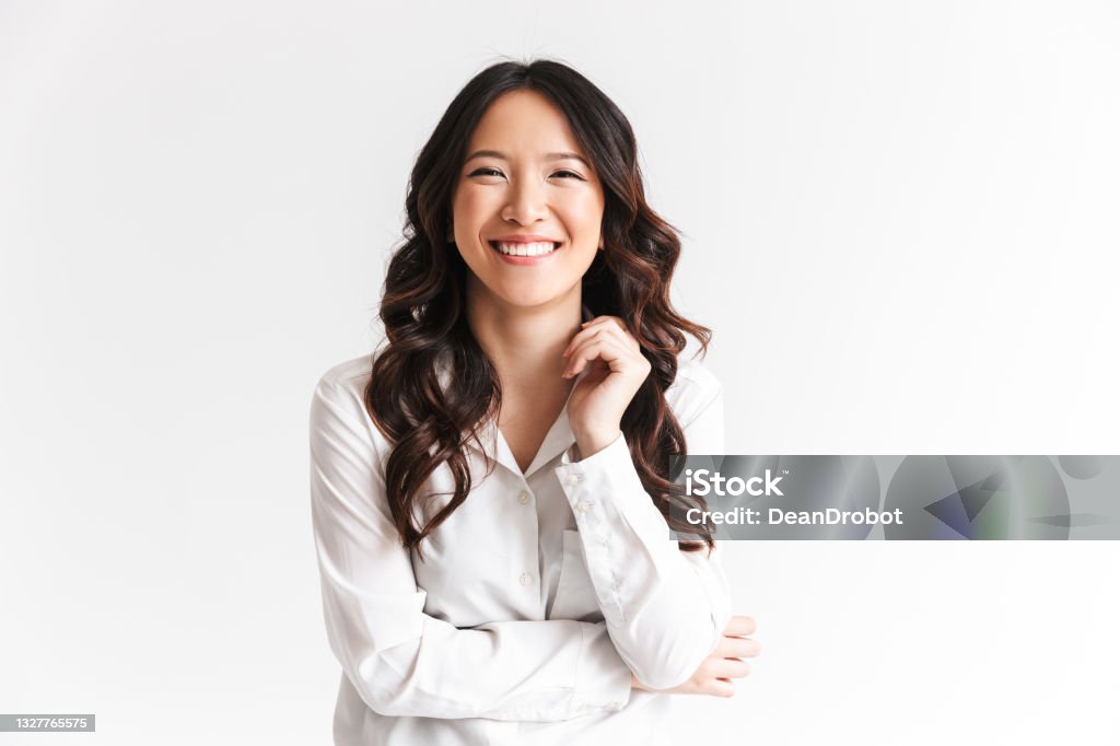 Portrait of gorgeous asian woman with long dark hair laughing at camera with beautiful smile, isolated over white background in studio Portrait of gorgeous asian woman with long dark hair laughing at camera with beautiful smile isolated over white background in studio Women Stock Photo