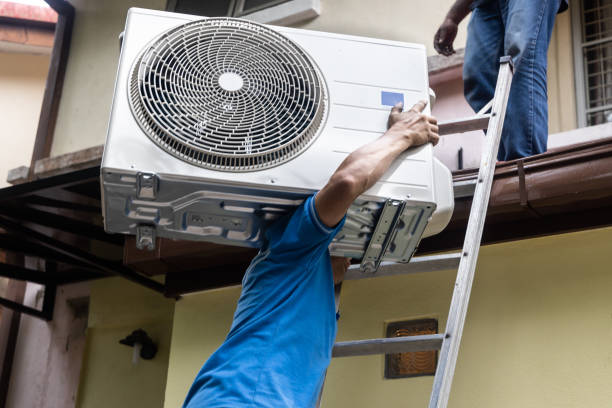 istock Technician transporting outdoor air conditioner compressor unit onto roof for installatiion 1327766636