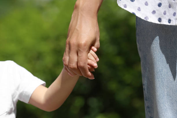 istock Mom and her child holding hands on blurred background, closeup 1327767096