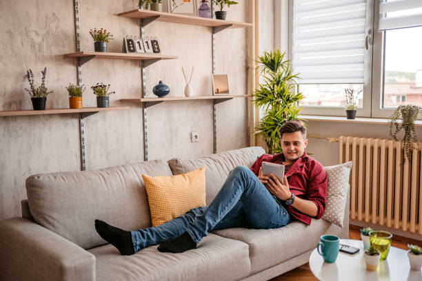 istock Man reading book on tablet at home 1327767340