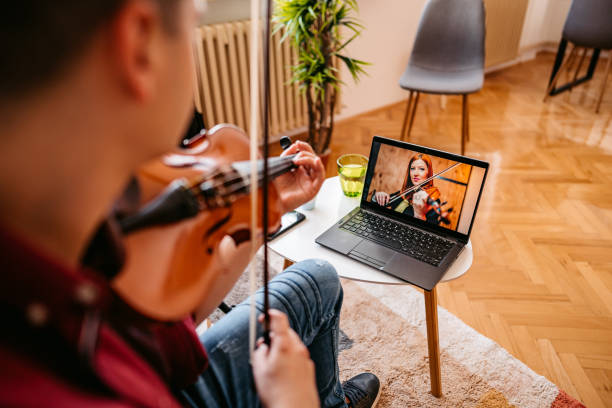 istock Man having online violin lesson on laptop 1327768006