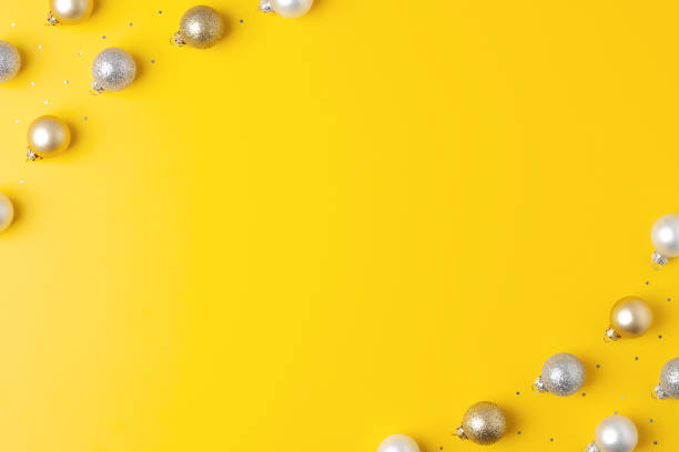 istock Christmas yellow minimal background with grey and beige ball and confetti. Flat lay, copy space 1327770401