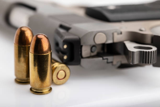 istock .45 or 11 mm. ammunitions and automatic hand gun on white background 1327773550