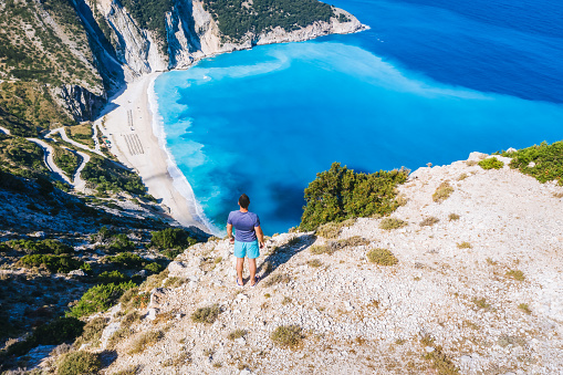 Un hombre de pie y disfrutando de la vista de la hermosa playa de Myrtos en Cefalonia, Grecia photo