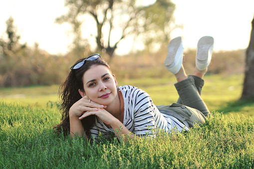 A beautiful black-haired girl is lying on the grass