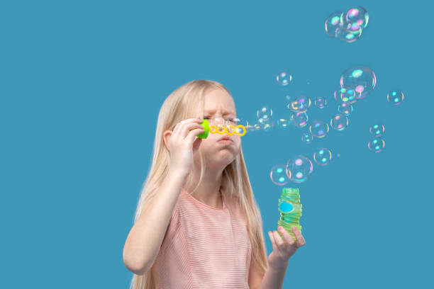 istock Adorable blonde girl blowing soap bubbles 1327776786