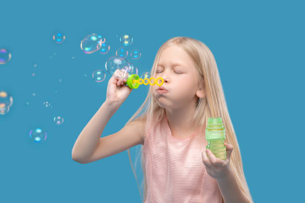istock Cute girl with closed eyes making soap bubbles 1327776788